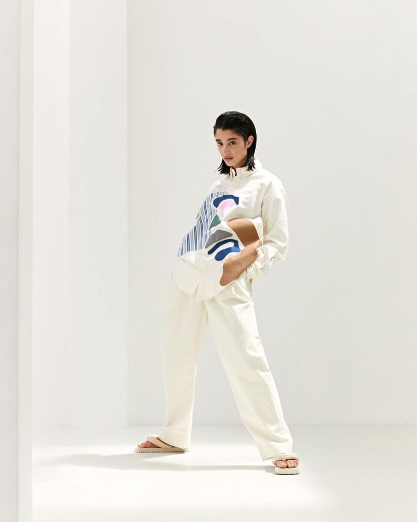 In studio picture of a model wearing Martan white trousers and printed shirt